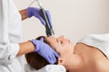 The cosmetologist makes the procedure an ultrasonic cleaning of the facial skin of a beautiful, young woman in a beauty salon. Royalty Free Stock Photo
