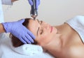 The cosmetologist makes the procedure an ultrasonic cleaning of the facial skin of a beautiful, young woman in a beauty salon Royalty Free Stock Photo
