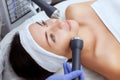 The cosmetologist makes the procedure an ultrasonic cleaning of the facial skin of a beautiful, young woman in a beauty salon