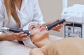 The cosmetologist makes the procedure an ultrasonic cleaning of the facial skin of a beautiful, young woman