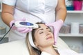 Cosmetologist makes an ultrasonic cleaning of the face of a young woman Royalty Free Stock Photo