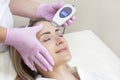 Cosmetologist makes an ultrasonic cleaning of the face of a young woman. Royalty Free Stock Photo