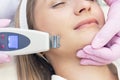 Cosmetologist makes an ultrasonic cleaning of the face of a young woman. Royalty Free Stock Photo