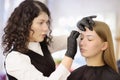 Cosmetologist making eyebrows makeup. Attractive woman getting facial care at beauty salon. Architecture eyebrows Royalty Free Stock Photo