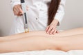 Cosmetologist making laser epilation on the girl`s calf and thighs.