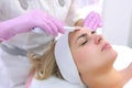 Cosmetologist makes ultrasonic face cleaning procedure to young woman in clinic. Royalty Free Stock Photo