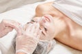 Cosmetologist massages cream mask into woman face skin for rejuvenation, procedure in beauty salon