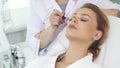 Cosmetologist moves iontophoresis roller along client`s forehead