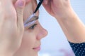 Cosmetologist painting brush shape of eyebrows woman before tint procedure.