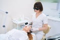 Cosmetologist performing forehead photorejuvenation procedure for lady