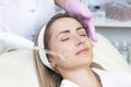 Cosmetologist performs a pulse current procedure for the face of a young woman