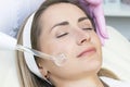 Cosmetologist performs a pulse current procedure for the face of a young woman