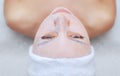 The cosmetologist for procedure of cleansing and moisturizing the skin, applying a sheet mask to the face of a young woman in beau