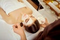 Cosmetologist puts a mask from cream on girl`s face in the spa s