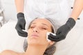 Cosmetologist removing facial cream mask from woman face skin with cosmetic wipes in beauty salon