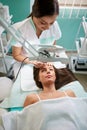 cosmetologist treats the face of a woman looking through a magnifying glass Royalty Free Stock Photo