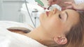 Cosmetologist using ultrasonic scrubber on client`s face