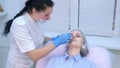 Cosmetologist wiping cream with anesthetic from face before biorevitalization.