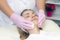 Cosmetology. Close up picture of lovely young woman with closed eyes receiving facial cleansing procedure