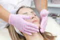 Cosmetology. Close up picture of lovely young woman with closed eyes receiving facial cleansing procedure