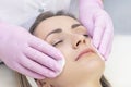 Cosmetology. Close up picture of lovely young woman with closed eyes receiving facial cleansing procedure