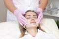 Cosmetology. Close up picture of lovely young woman with closed eyes receiving facial cleansing procedure