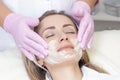Cosmetology. Close up picture of lovely young woman with closed eyes receiving facial cleansing procedure