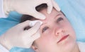 Cosmetology, consequences after beauty injections on the woman`s forehead, removed with a cotton pad Royalty Free Stock Photo
