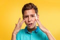 Cosmetology, Dermatology and acne. A Caucasian teenager in a blue t-shirt is upset about the appearance of acne. Yellow background