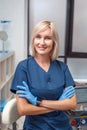 Cosmetology Service. Young doctor in gloves at beauty clinic standing crossed arms smiling confident