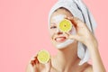 Cosmetology, skin care, face treatment, spa and natural beauty concept. Woman with facial mask holds lemons Royalty Free Stock Photo