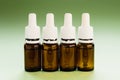 cosmetology, skin care, a row of glass bottles with pipettes and hyaluronic acid inside on a green background