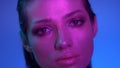 Cosmical fashion model in violet neon lights slowly moving and closing eyes to show glitter makeup in studio.