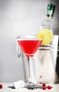 Cosmopolitan alcoholic cocktail drink with vodka, liqueur, cranberry juice, lime and ice. Gray table background, bar tools, copy