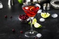 Cosmopolitan cocktail with vodka, liqueur, cranberry juice, lime, ice and orange zest, gray bar counter background, bartender Royalty Free Stock Photo