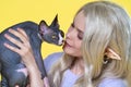 Cosplayer elf young blonde woman in blue dress with curly long hair caresses Sphinx kitten Royalty Free Stock Photo