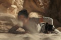 Cosplayer girl portrays character Rey Skywalker from the Star Wars universe and lies down in desert against background of flying