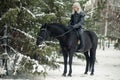 Cosplayer in image of a character Geralt of Rivia from the game or series The Witcher riding a horse winter forest