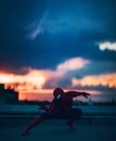 Cosplayer in image of a character Spider-Man poses in roof of building at sunset
