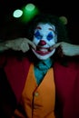 Cosplayer in the image of a clown grimaces at nigth city