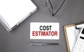 COST ESTIMATOR Text written on the card with notebook and clipboard, grey background