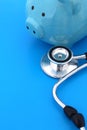 On a blue background lies a stethoscope and a piggy bank. Royalty Free Stock Photo