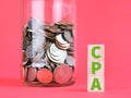 Text CPA on wooden cubes with coins against red background.