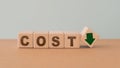 COST text on wooden cube block with green down arrow including copy space