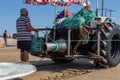 Costa da Caparica, Portugal - September 10, 2020: An artel of fishermen trawls fish from the tourist beach using a tractors.