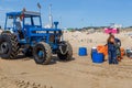 Costa da Caparica, Portugal - September 10, 2020: An artel of fishermen trawls fish from the tourist beach using a tractors.