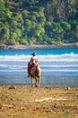Costa Rican cowboy riding his horse on the beach