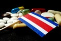 Costa Rican flag with lot of medical pills isolated on black background Royalty Free Stock Photo