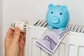 costs of heating apartments in winter in Denmark, Energy and economic concept, Hand unscrewing the radiator, piggy bank and 50