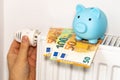 costs of heating apartments in winter in the European Union, energy and economic concept, hand unscrewing the radiator, piggy bank